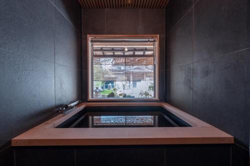 a bath tub in a room with a window at 飛騨高山一の響 in Wada