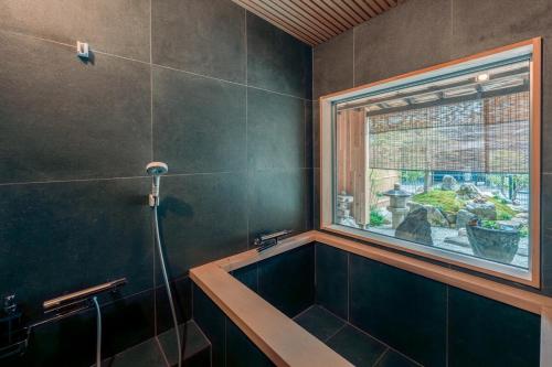 a bathroom with a bath tub and a window at 飛騨高山一の響 in Wada
