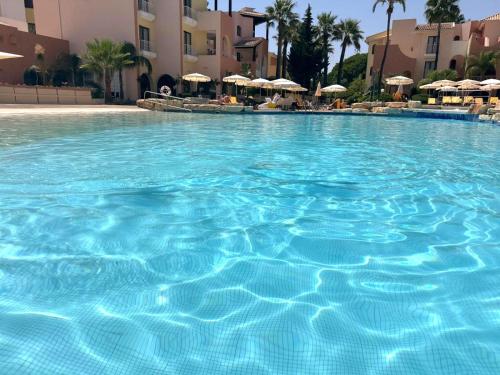 a large pool of blue water with umbrellas at FourSeasons Vilamoura in Quarteira