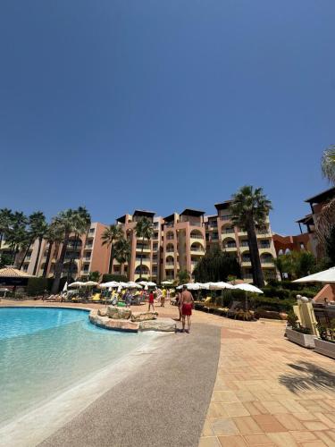 a person walking by a swimming pool in a resort at FourSeasons Vilamoura in Quarteira