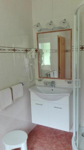 a white bathroom with a sink and a mirror at Pensione Valbona in Corvara in Badia