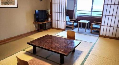 a living room with a table and a tv at Kirishima Onsen Ryokojin Sanso in Kirishima