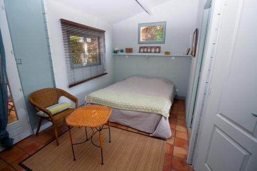 a small bedroom with a bed and a table and chair at Pousterle de Sabran - Piscine & Hammam in Sabran