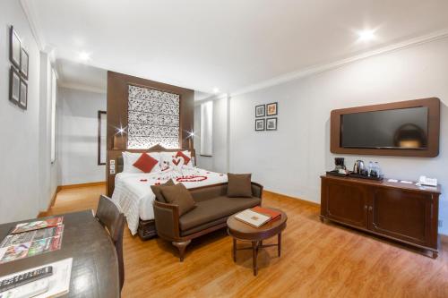 a bedroom with a bed and a couch and a tv at The Lokha Legian Resort & Spa in Legian