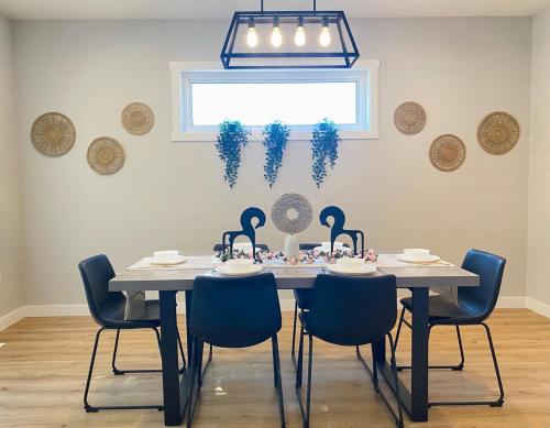 a dining room table with blue chairs and a chandelier at The Downtown Oasis - A Spacious Family Friendly 3 Bedroom House Close to Everything in Edmonton