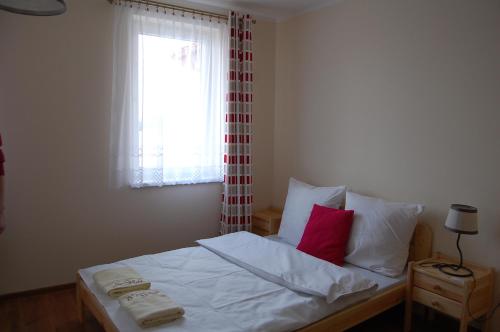 a bedroom with a bed with white sheets and red pillows at Przystanek Czapla in Czaplinek