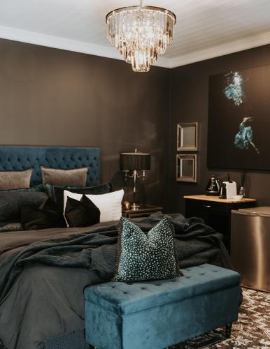 a bedroom with a blue bed and a chandelier at Calstock Estate 1831 in Deloraine