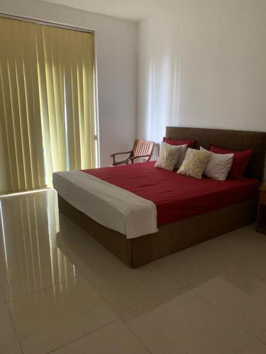 a bedroom with a bed with red sheets and a window at R&R residencies in Mount Lavinia