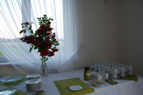 a white table with a vase of red flowers on it at Przystanek Czapla in Czaplinek
