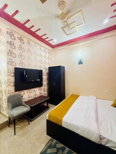 a bedroom with a bed and a desk and a tv at Hotel Chandra Dreams in Varanasi