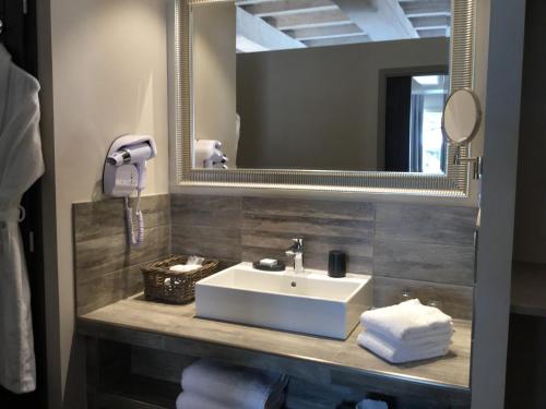 a bathroom with a sink and a mirror at Boutique Hôtel La Villa MONTESQUIEU in Laudun
