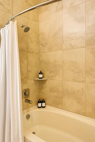a bathroom with a tub and a shower curtain at Lux Modern Apartment with Pool View & Prime Location in Frisco