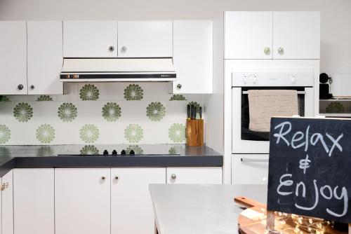 a kitchen with white cabinets and a sign that says relax everyday at Anembo Country Cottages in Eatons Hill