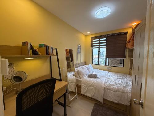 a bedroom with a bed and a desk and a window at Elly's Place in Quezon City