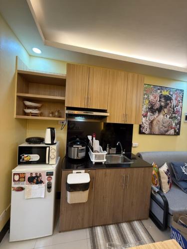 a small kitchen with a refrigerator and a sink at Elly's Place in Quezon City