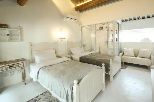 a white bedroom with two beds and a chair at Goodnight hotel in the ancient Hutong in Beijing