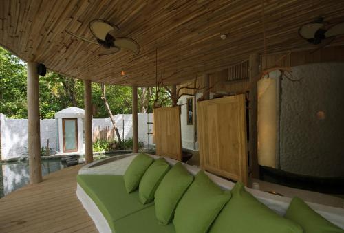 a room with a bed with green pillows on it at Soneva Fushi in Baa Atoll