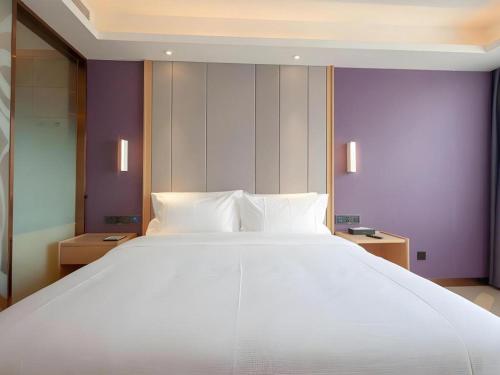 a large white bed in a room with purple walls at Lavande Hotel Changsha South High-speed Railway Station Xiyingmen in Changsha