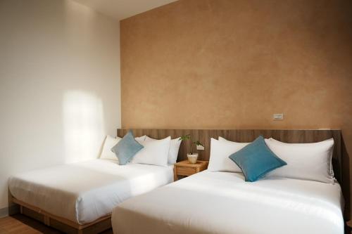 two beds in a hotel room with blue pillows at 循跡文旅 Tracöver 
