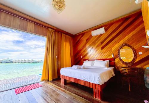 a bedroom with a bed and a large window at Noura Resort Semporna in Semporna