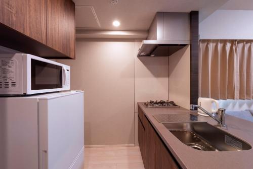 a small kitchen with a sink and a microwave at Hostel Inn Tokyo Asakusa Annex in Tokyo
