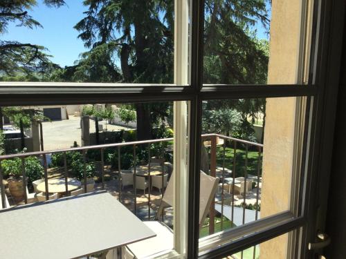 a window view of a balcony with a table and chairs at Boutique Hôtel La Villa MONTESQUIEU in Laudun