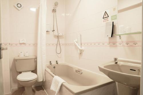 a white bathroom with a toilet and a sink at The Seafront Hotel by Compass Hospitality in Llandudno