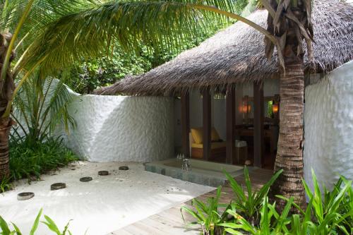 a bathroom with a bath tub next to a building at Soneva Fushi in Baa Atoll