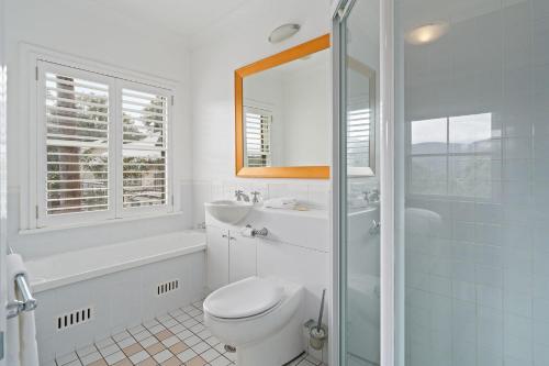 a bathroom with a toilet and a sink and a shower at Golf & Wine Country Villa Cypress in Pokolbin