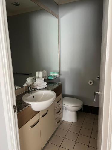 a bathroom with a sink and a toilet and a mirror at Caloundra Central Apartment Hotel Official in Caloundra