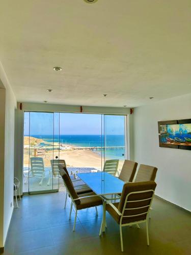 a dining room with a table and chairs and the ocean at Casa Bahía El Ñuro in El Ñuro