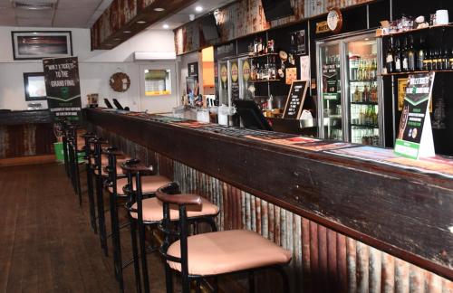 una fila de taburetes en una barra de un pub en Leichhardt Hotel, en Taroom
