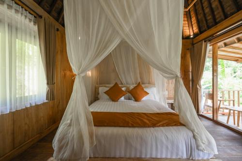 a bedroom with a bed with a mosquito net at Keuma Villa & Resto Jatiluwih by The Lavana in Jatiluwih
