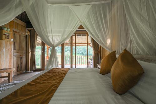 a bedroom with a bed with a canopy at Keuma Villa & Resto Jatiluwih by The Lavana in Jatiluwih