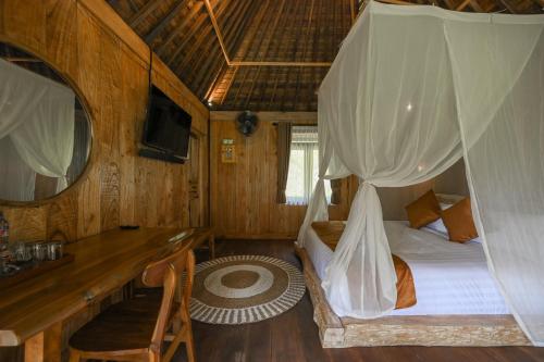 a bedroom with a bed and a desk in a room at Keuma Villa & Resto Jatiluwih by The Lavana in Jatiluwih