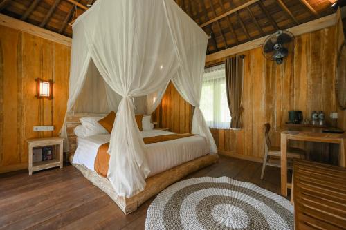 a bedroom with a bed with a canopy at Keuma Villa & Resto Jatiluwih by The Lavana in Jatiluwih