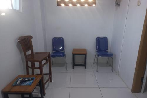 a room with two chairs and a table and a tv at OYO 94771 White House Arafah Syariah in Purwokerto