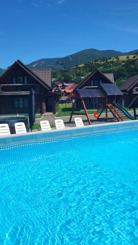 a large swimming pool with chairs and a house at Котеджі Карпати Fest in Mizhhirʼʼya