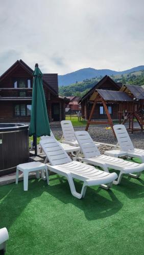 a group of lawn chairs and a green umbrella at Котеджі Карпати Fest in Mizhhirʼʼya