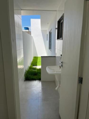 a white bathroom with a sink and a green lawn at Colares House Pedra de Guaratiba - 2 quartos - style and comfort in Pedra de Guaratiba