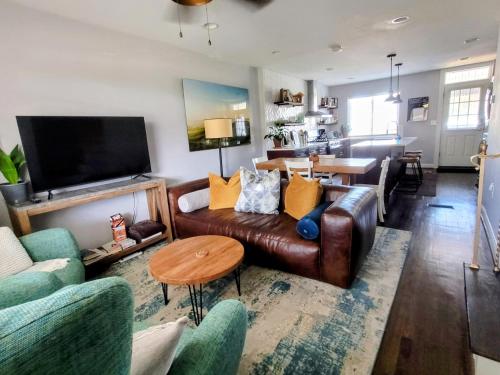 a living room with a leather couch and a table at Capitol Hill Adj Home with Parking and Easy Access to Downtown in Washington, D.C.