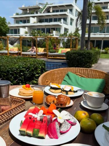 a table with plates of food and fruit on it at Selina Serenity Rawai Phuket in Rawai Beach