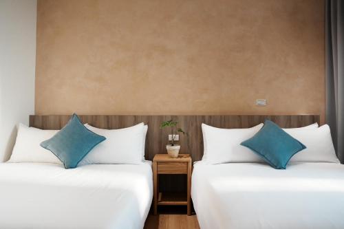 two beds in a hotel room with blue pillows at 循跡文旅 Tracöver 
