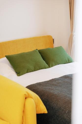 a bed with two green pillows on top of it at 寅ホテル新江古田TORA HOTELShinEkoda in Tokyo