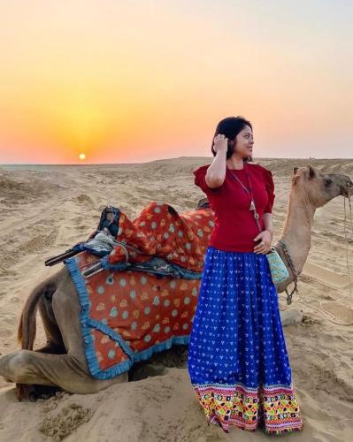 a woman talking on a cell phone next to a camel at The Desert Resort Jaisalmer in Jaisalmer