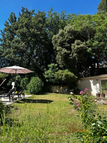 a picnic table and an umbrella in a yard at Cocon cosy appart romantique, jacuzzi piscine in Puget
