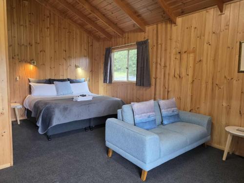 a bedroom with a bed and a couch and a chair at Maydena Mountain Cabins in Maydena