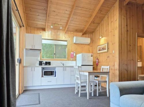 a kitchen with white cabinets and a table and chairs at Maydena Mountain Cabins in Maydena