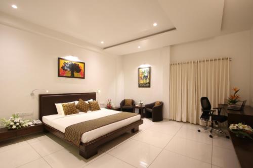 una camera da letto con un letto, una scrivania e delle sedie di Prakruti Resort a Vadodara