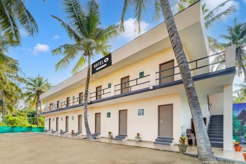 a building with palm trees in front of it at Super Hotel O Avinashi Road Coimbatore in Coimbatore